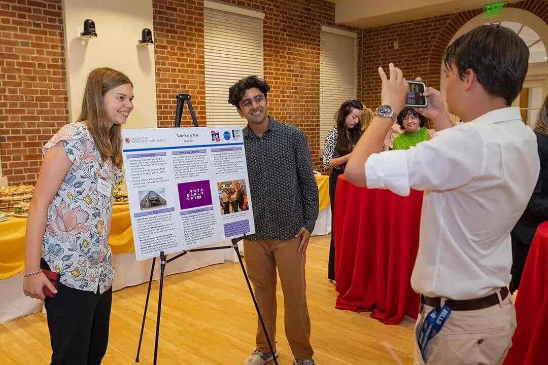 people speaking while looking at a poster