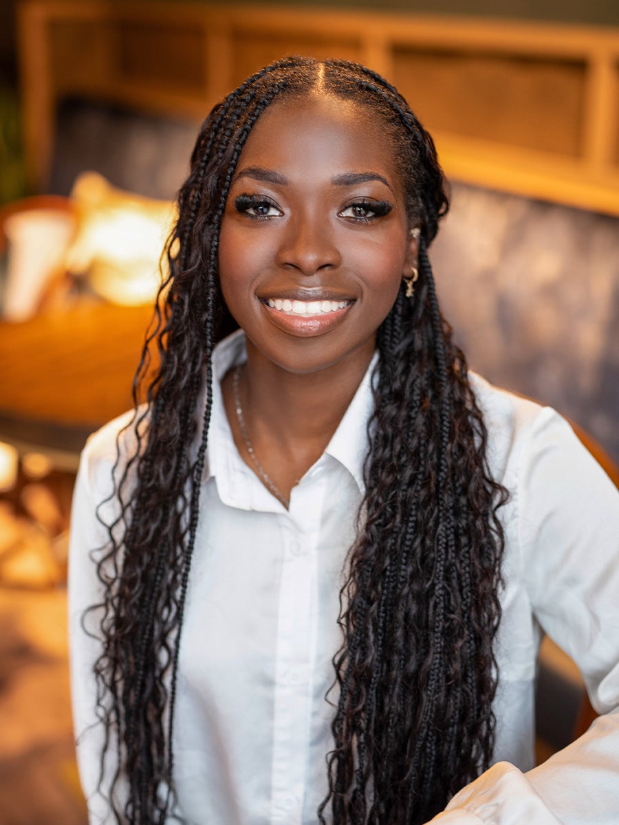 Favour Gam's headshot is a woman with braids smiling with a white collar shirt