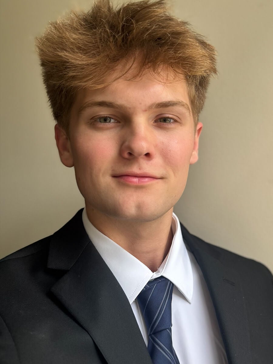 Headshot of student wearing black suit and tie
