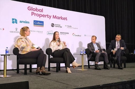 4 people sitting on a stage (panel discussion) with white background behind them