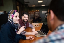 Image of three people sitting around a table having a discussion