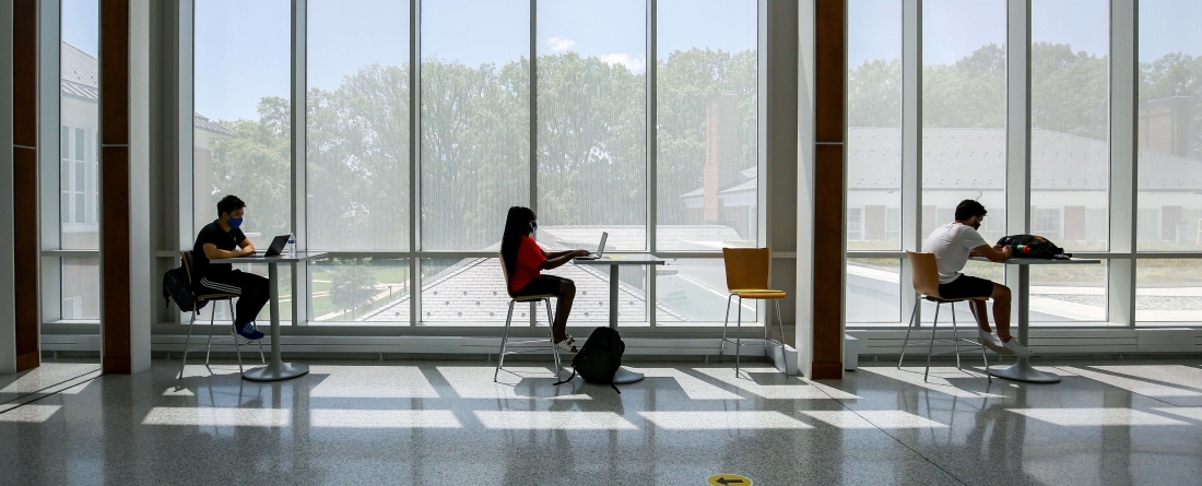 students in masks studying on laptops