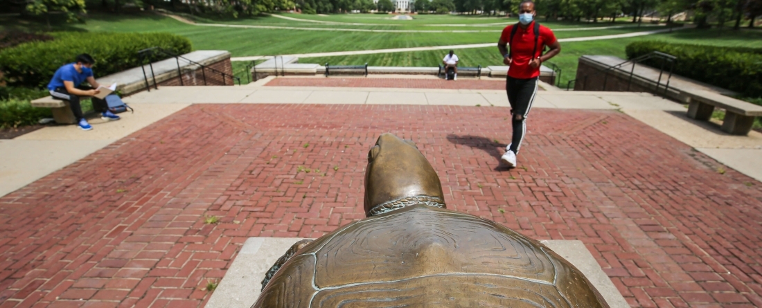 students wearing masks approaching testudo on mckeldin mall