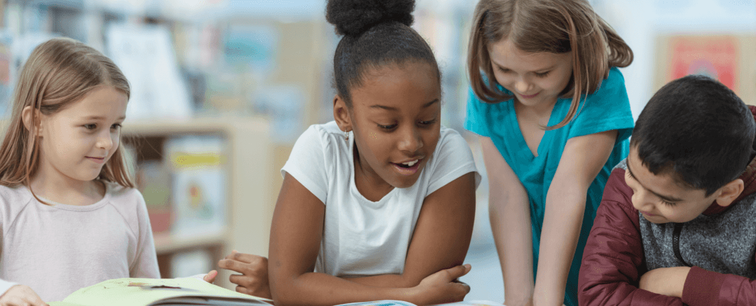 Diverse group of young children reading a book in a library