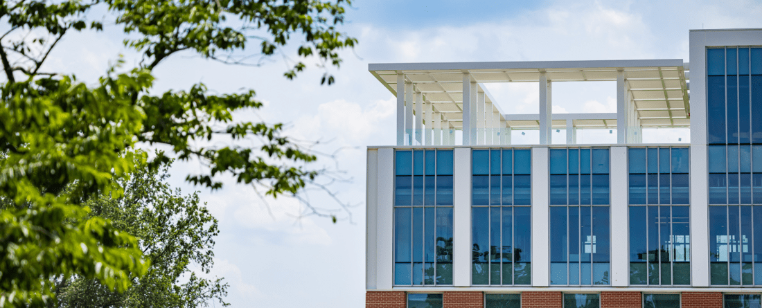 Corner of new building with trees in the foreground.