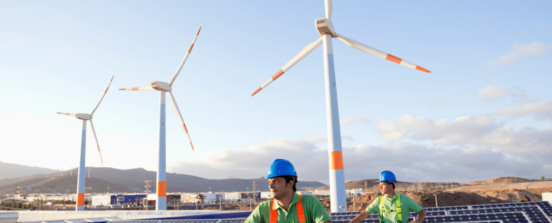 photo of solar panels, wind mills, and people