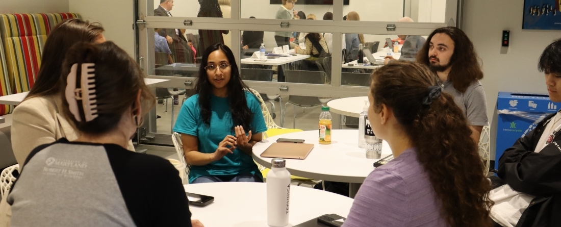 Students gathered around a white table with a garage door behind them in the Do Good Accelerator