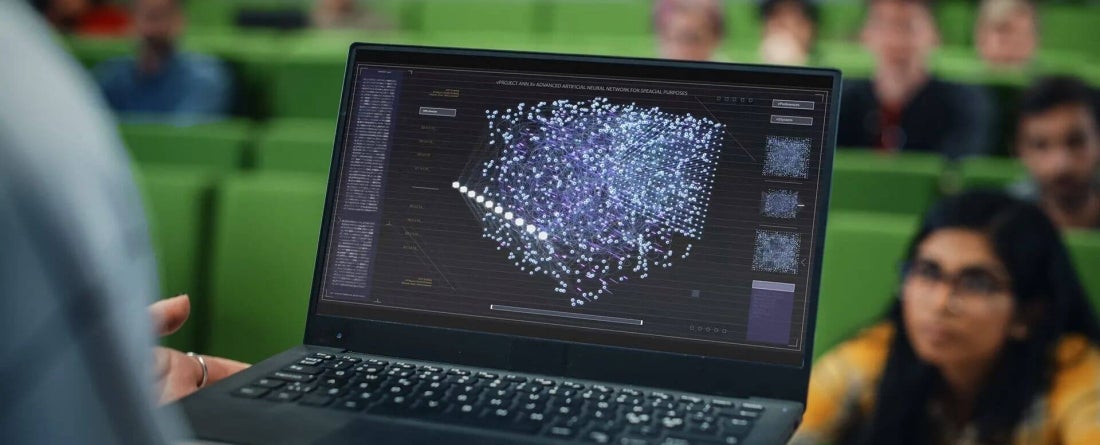 Laptop screen displaying an artificial intelligence network diagram as students look on in a classroom.