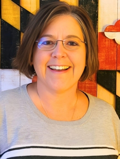 Nancy Lineman standing against a backdrop of the Maryland flag